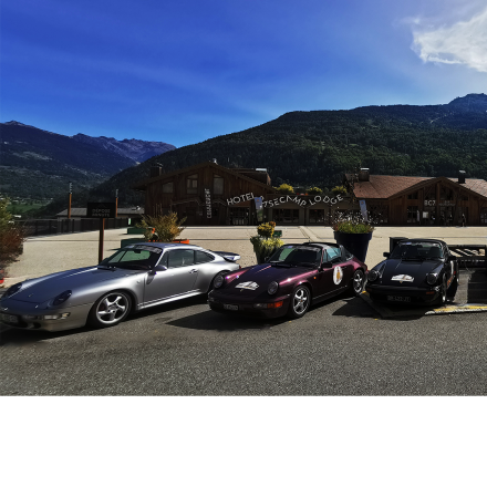 Club Porsche Savoie lors de son événement à l'Hôtel Base Camp Lodge - Des voitures de sport élégantes entourées par les Alpes françaises.